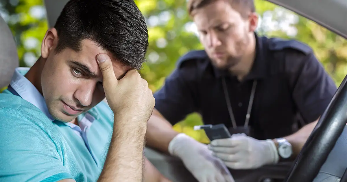 Young Sad Driver And A Policeman Looking At A Breathalyser